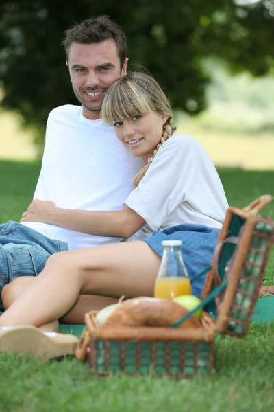 Jovem casal desfrutando de piquenique — Fotografia de Stock
