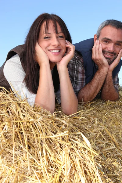 Casal de agricultores relaxando em um fardo de palha — Fotografia de Stock