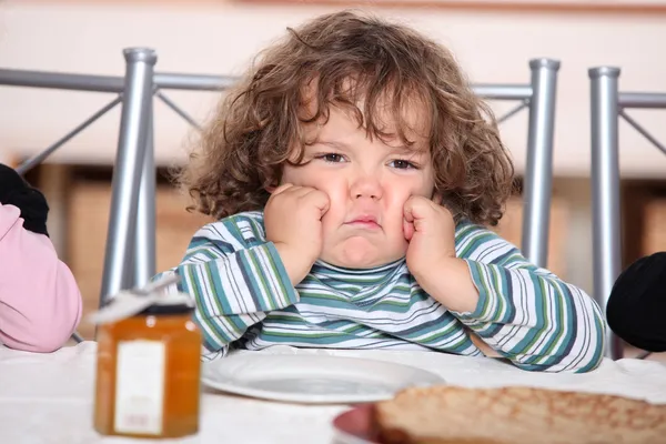 Pequeño niño grouching en frente de un plato de crepes — Foto de Stock