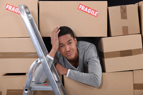 Jonge man omringd door dozen verplaatsen naar een nieuwe appartement — Stockfoto