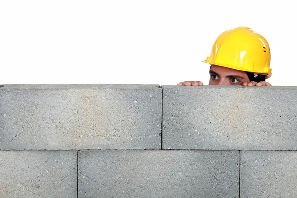 Craftsman hiding behind a stone wall — Stock Photo, Image
