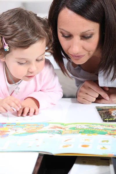 Moeder en kind op zoek naar een boek — Stockfoto