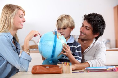 Little boy doing homework with his parents clipart