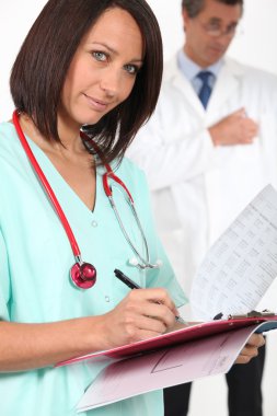 Medical professional filling in a patient record clipart