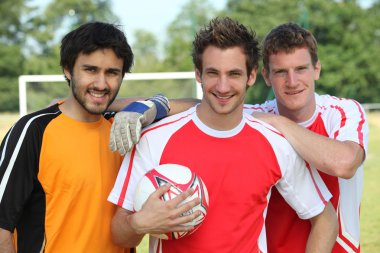 Three footballers in front of goal clipart