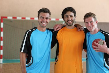 Three grinning footballers in front of goal clipart