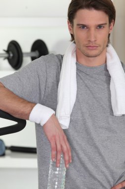 Serious man with a bottle of water in the gym clipart