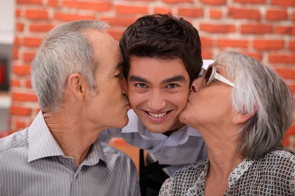 Grandparents kissing their adult grandson — Stok fotoğraf