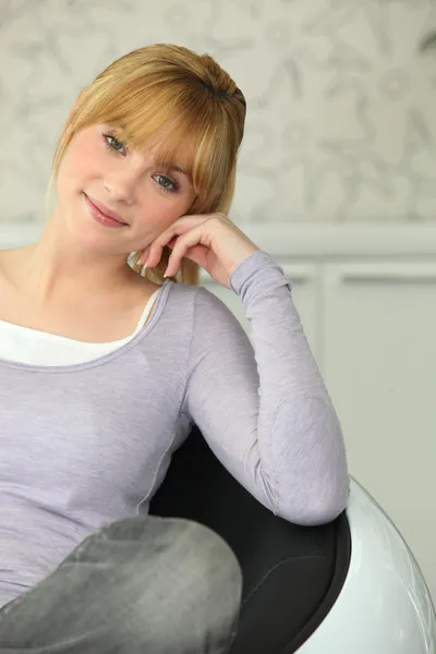 Młoda blond dziewczyna siedzi w fotelu — Zdjęcie stockowe