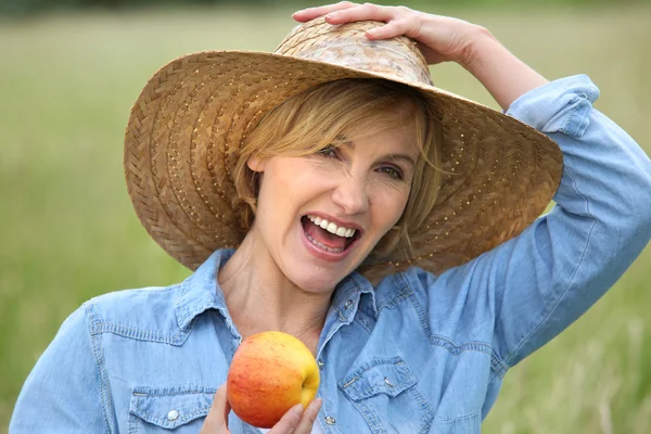 Vrouw in stro hoed eten apple — Stockfoto