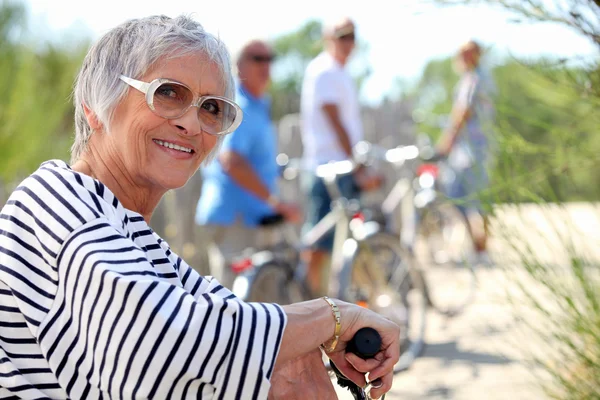 65 år gammal kvinna gör cykeln i landet med vänner — Stockfoto