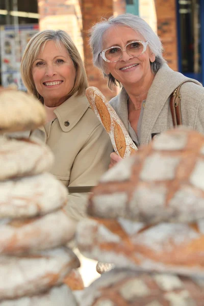 A 50 years old woman and a 70 years old woman in a bakery — Stock Photo, Image