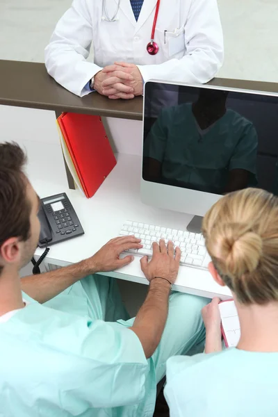 Orvosi asszisztens nézi a tükörképét a számítógép képernyőjén — Stock Fotó