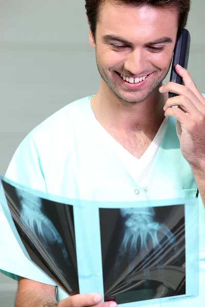 Lékař zkoumá rentgen při rozhovoru na telefonu — Stock fotografie