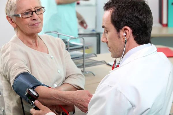 Dottore che controlla la pressione sanguigna di una signora anziana — Foto Stock