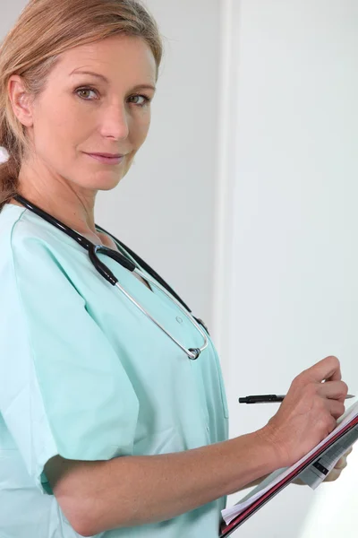 Женщина-медсестра держит планшет и ручку — стоковое фото