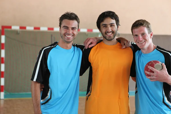 Drie grijnzende voetballers voor doel — Stockfoto