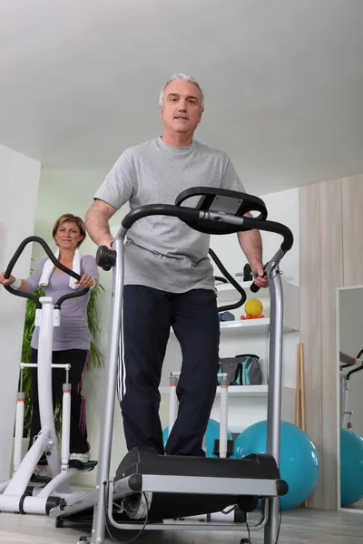 Couple working out on treadmill and cycle machine — Stock Photo, Image