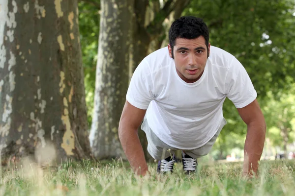 Uomo muscolare che fa flessioni in un parco — Foto Stock