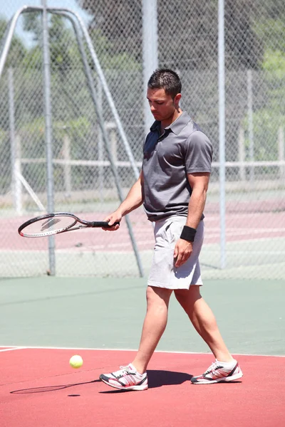 Hombre de pie en la cancha de tenis al aire libre rebotando pelota con raqueta —  Fotos de Stock