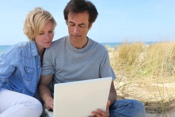 Casal no laptop na praia — Fotografia de Stock