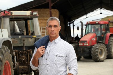 A farmer posing with his tractors clipart