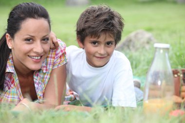 Mother and son lying in the grass clipart