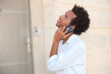 A man at phone in front of a closed door clipart