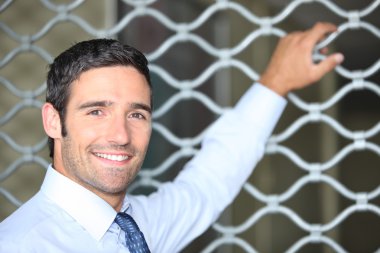 Smiling man standing in front of a shop grille clipart