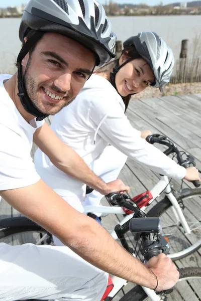 Молода пара катається на велосипеді вздовж річки — стокове фото