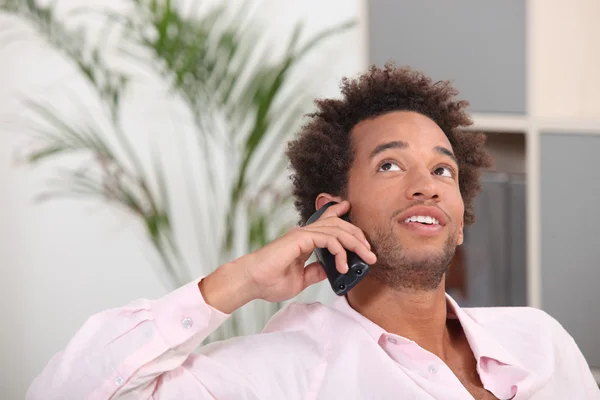 Genç Afro-Amerikan evde cep telefonundan konuşuyor — Stok fotoğraf