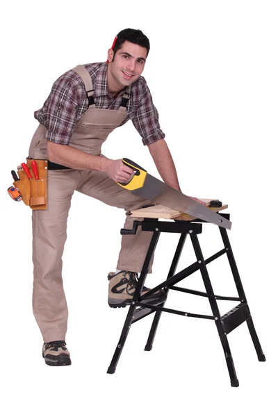 Carpinteiro usando uma serra manual — Fotografia de Stock