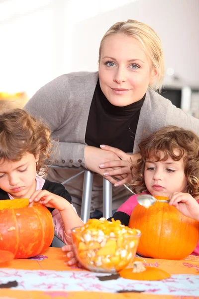 Woman helping her children carve pumpkins — Stock Photo, Image