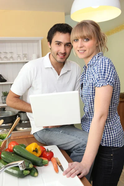 Paar koken en met behulp van een laptop — Stockfoto