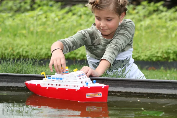 Школьница играет с пластиковой лодкой — стоковое фото