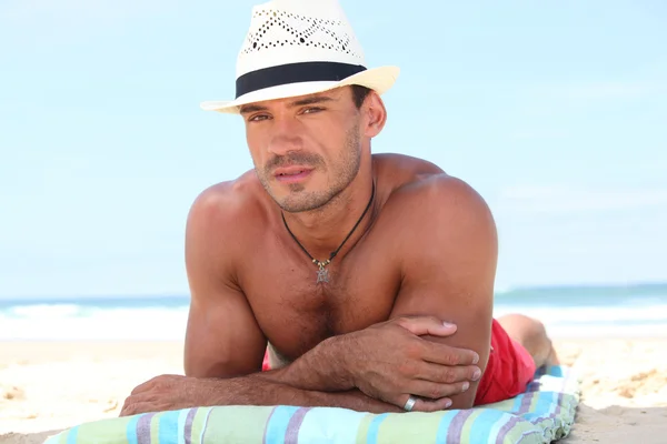 Homem deitado na praia com um chapéu de palha — Fotografia de Stock