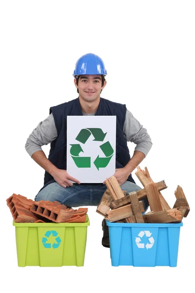 stock image Craftsman holding a recycling label over two boxes of used materials