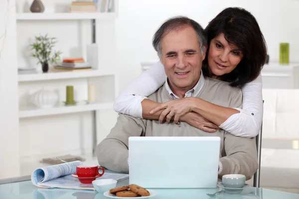 Um casal de meia idade olhando para um laptop . — Fotografia de Stock