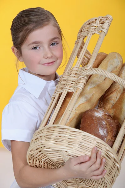 Маленькая девочка с корзиной багетов — стоковое фото