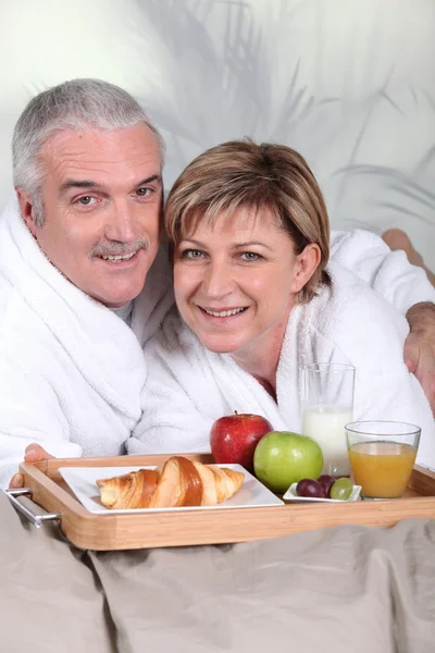 Średnim wieku para o śniadanie w łóżku — Zdjęcie stockowe