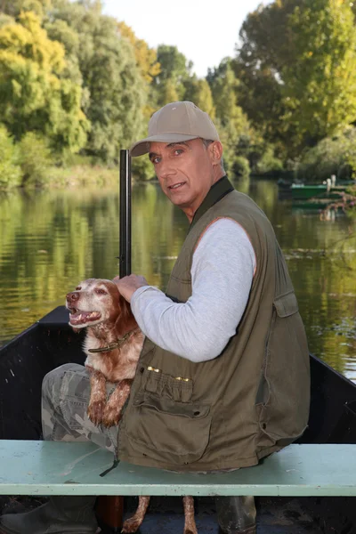 Hunter on a boat with his dog — Stock Photo, Image