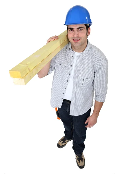 A male carpenter carrying a plank. — Stock Photo, Image