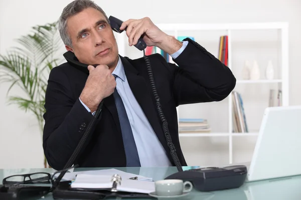Businessman answering ringing telephones — Stock Photo, Image