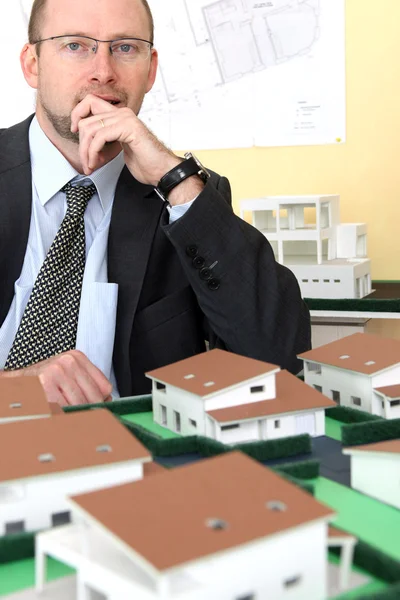 Pensive architect sat with model housing project — Stock Photo, Image