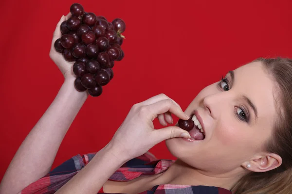 Mulher comendo um monte de uvas vermelhas — Fotografia de Stock