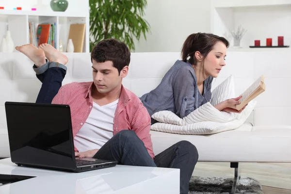 Couple reading a book and a laptop — Stock Photo, Image