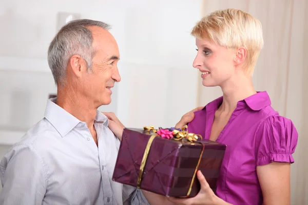 Young woman giving a gift to an older man