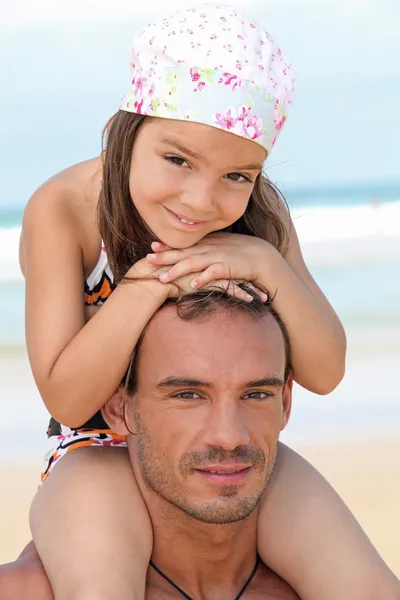 Kleines Mädchen sitzt auf den Schultern des Vaters am Strand — Stockfoto