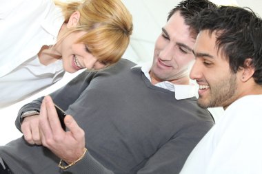 Three looking at mobile telephone screen clipart