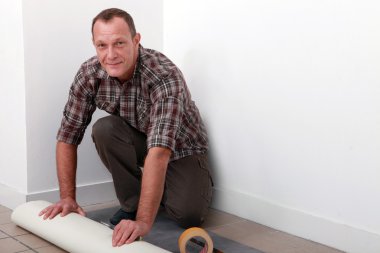 Man putting down linoleum flooring clipart